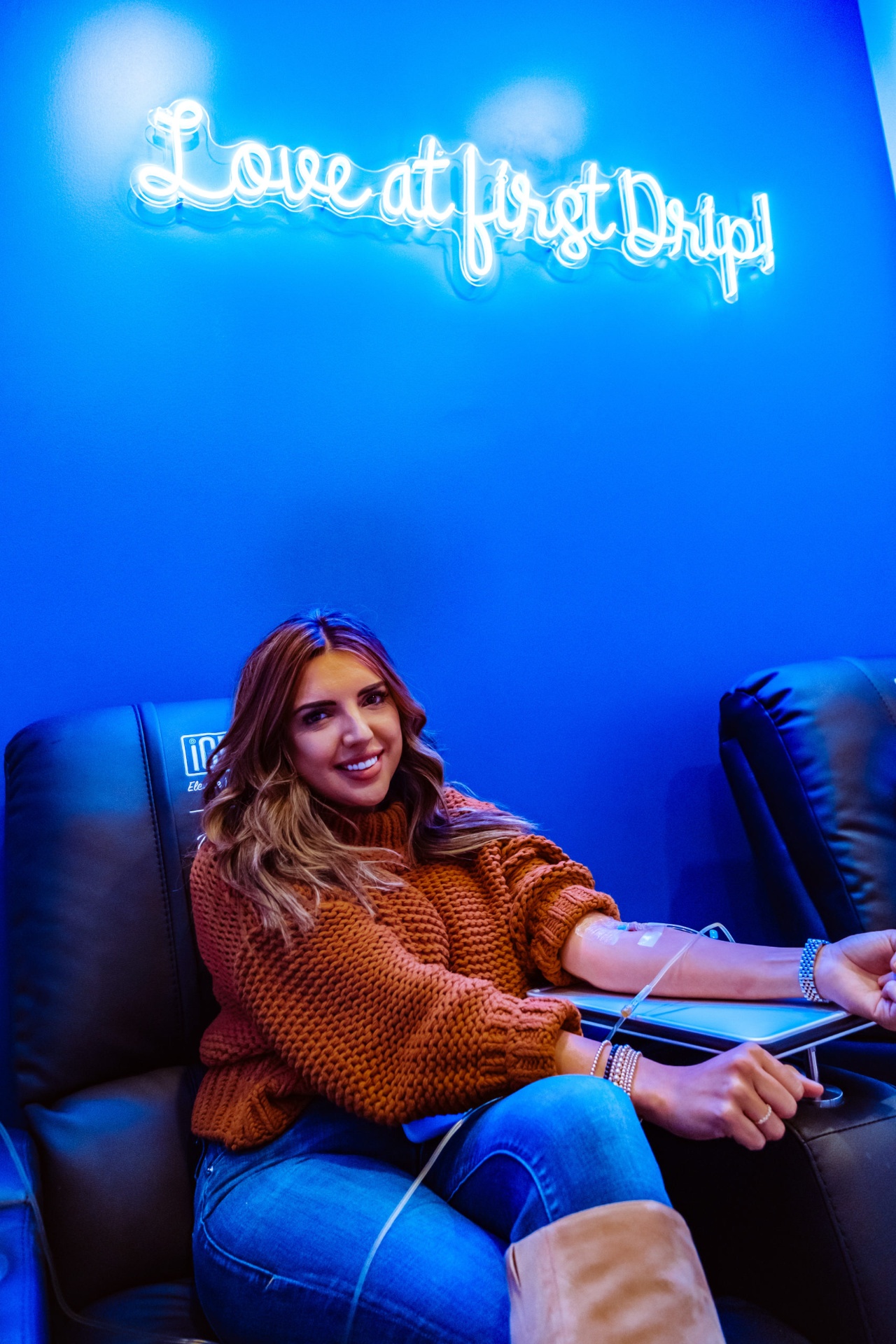 iCRYO Helotes guest receiving an IV drip under the Love at First Drip neon